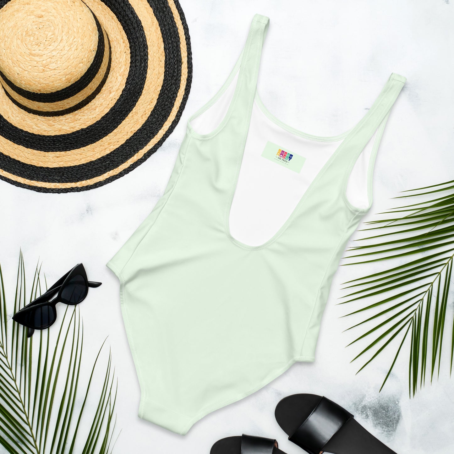 One piece swimsuit with a painted heart motive on a light green background - back
