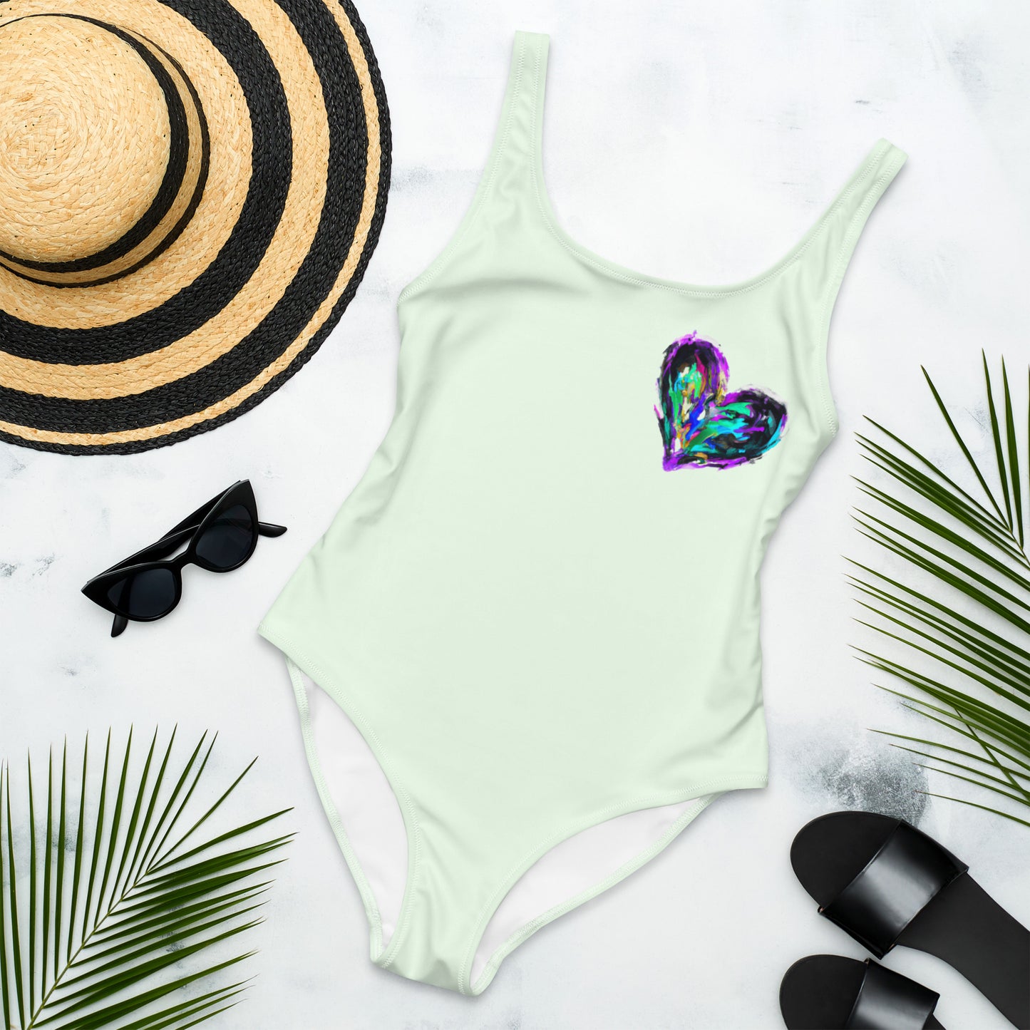 One piece swimsuit with a painted heart motive on a light green background - front